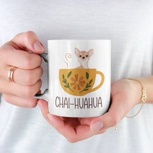 May include: White ceramic mug with a brown chihuahua sitting in a yellow teacup with a floral design. The text "Chai-huahua" is printed on the mug.
