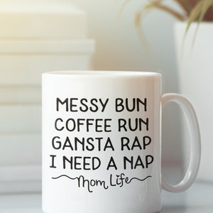 Pode incluir: Caneca de caf&eacute; de cer&acirc;mica branca com texto preto que diz "Messy Bun Coffee Run Gansta Rap I Need A Nap Mom Life".