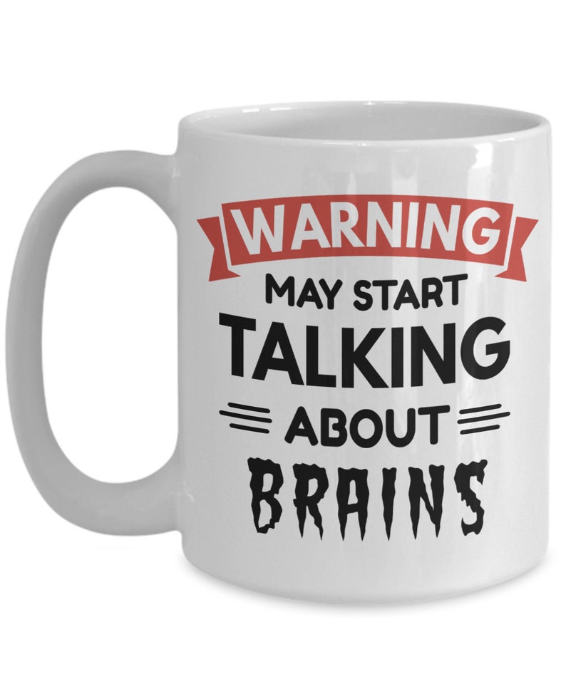 May include: White ceramic coffee mug with a black and red design. The text on the mug reads "WARNING MAY START TALKING ABOUT BRAINS".