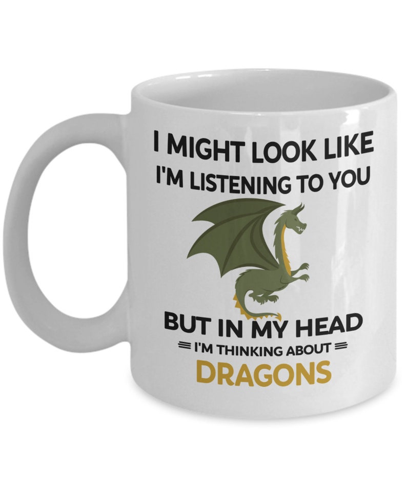 Puede incluir: Taza de caf&eacute; de cer&aacute;mica blanca con una ilustraci&oacute;n de drag&oacute;n verde y el texto "Puede que parezca que te estoy escuchando, pero en mi cabeza estoy pensando en dragones."