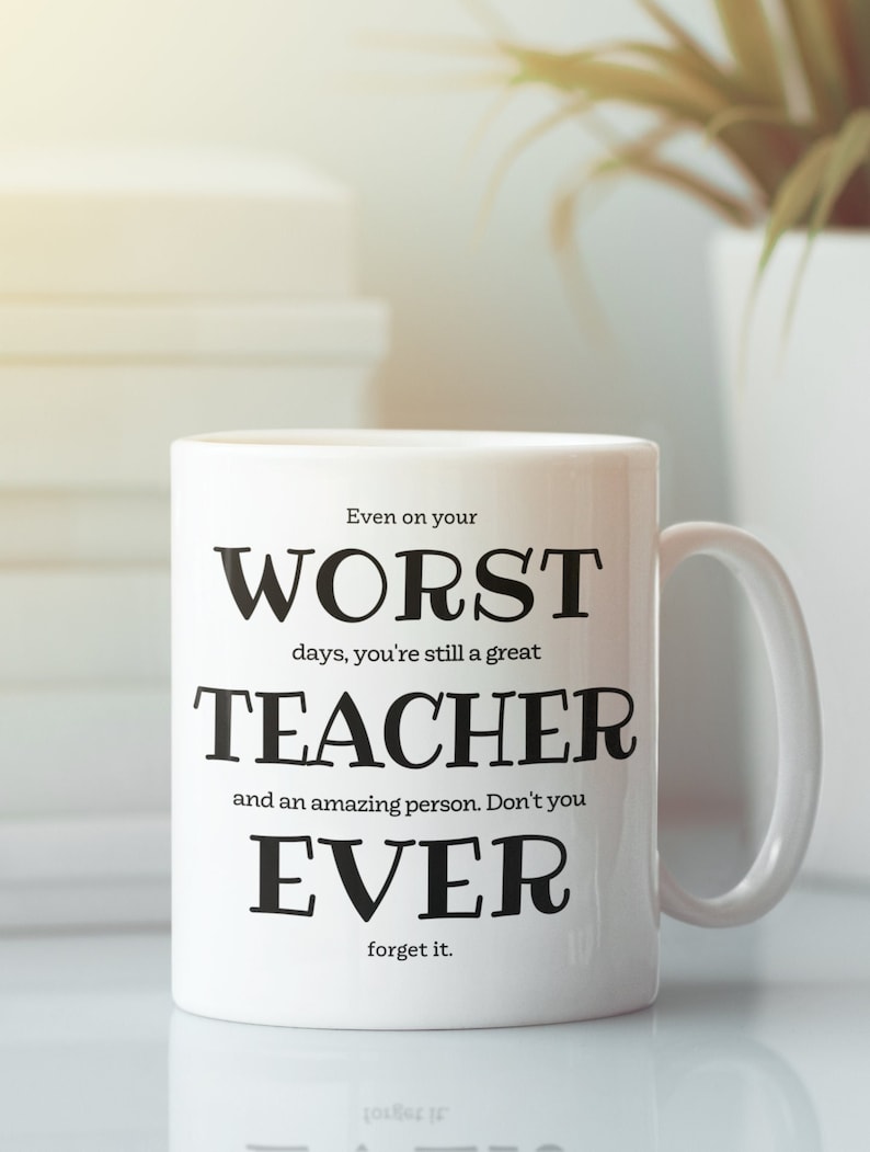 May include: White ceramic mug with black text that reads "Even on your worst days, you're still a great teacher and an amazing person. Don't you ever forget it."