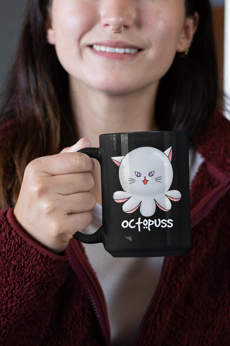 May include: A black coffee mug with a white octopus with pink tentacles and purple eyes. The octopus has a cat face and the text "octopus" is written below it.