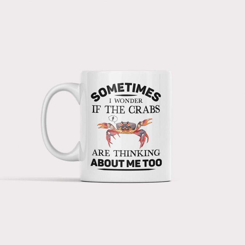 Op de afbeelding: Een witte keramische mok met een zwart-witte afbeelding van een krab en de tekst "Sometimes I wonder if the crabs are thinking about me too."