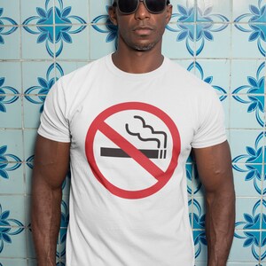 May include: A white t-shirt with a red circle and a diagonal line through it. The circle contains a black cigarette with smoke coming from it. The text "No Smoking" is not visible in the image.