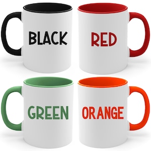 May include: Four ceramic mugs with different colored rims. The mugs are white with black, red, green, and orange rims. The words "BLACK", "RED", "GREEN", and "ORANGE" are printed on the mugs.