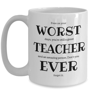 May include: White ceramic coffee mug with black text that reads "Even on your worst days, you're still a great teacher and an amazing person. Don't you ever forget it."