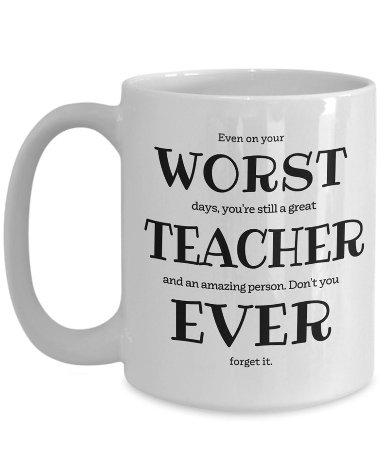 May include: White ceramic coffee mug with black text that reads "Even on your worst days, you're still a great teacher and an amazing person. Don't you ever forget it."