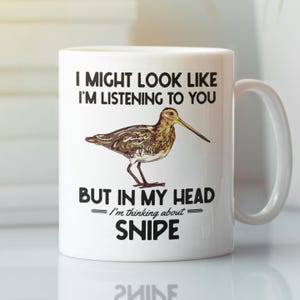 Może przedstawiać: Biały ceramiczny kubek do kawy z czarno-białym obrazkiem ptaka bekas. Tekst na kubku brzmi "I might look like I'm listening to you, but in my head I'm thinking about SNIPE."