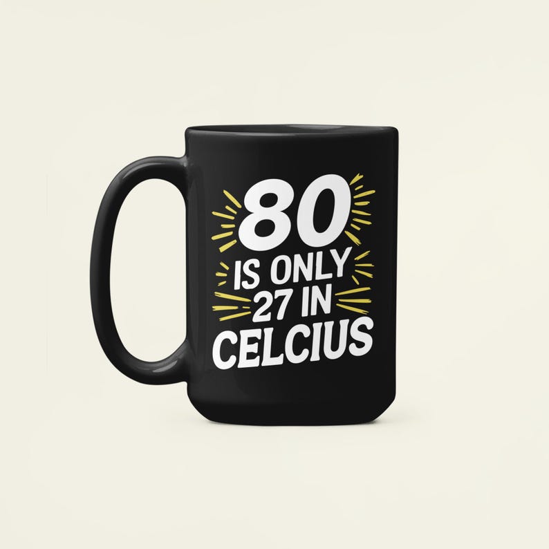 May include: Black ceramic mug with a white and yellow graphic. The graphic reads "80 is only 27 in Celcius". The mug has a large handle and is likely used for hot beverages.