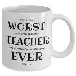 May include: White ceramic coffee mug with black text that reads "Even on your worst days, you're still a great teacher and an amazing person. Don't you ever forget it."