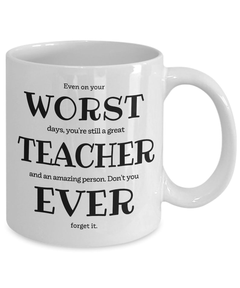 May include: White ceramic coffee mug with black text that reads "Even on your worst days, you're still a great teacher and an amazing person. Don't you ever forget it."
