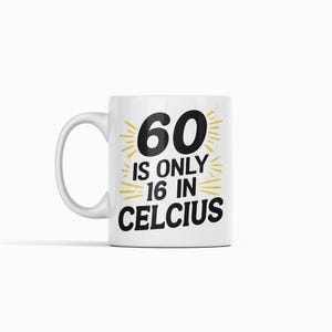 May include: White ceramic mug with the text "60 is only 16 in Celsius" in black and yellow. The mug has a curved handle and is set against a white background.