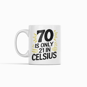 May include: White ceramic mug with a black and gold design. The mug features the number "70" with the text "is only 21 in Celsius". The design includes gold bursts around the numbers and text.