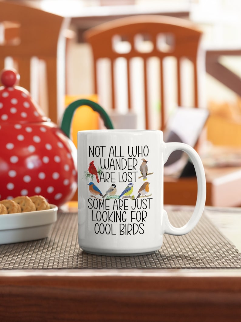 Puede incluir: Taza de caf&eacute; de cer&aacute;mica blanca con un dise&ntilde;o en blanco y negro que presenta una variedad de p&aacute;jaros y el texto "Not all who wander are lost. Some are just looking for cool birds."