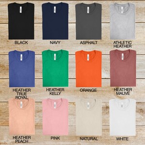 May include: A selection of t-shirts in various colors, including black, navy, asphalt, athletic heather, heather true royal, heather kelly, orange, heather mauve, heather peach, pink, natural, and white.