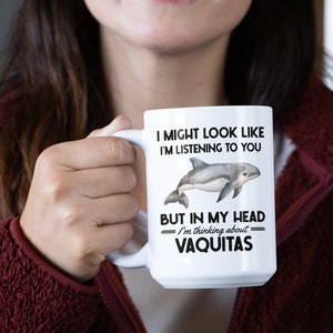 May include: White ceramic mug with a black and white graphic of a vaquita, a small porpoise. The text on the mug reads "I might look like I'm listening to you, but in my head I'm thinking about vaquitas."