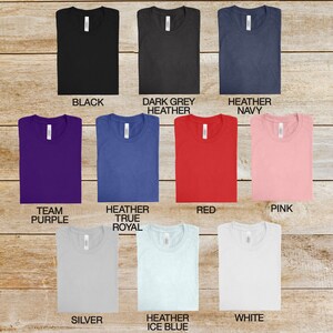 May include: A selection of t-shirts in various colors, including black, dark grey heather, heather navy, team purple, heather true royal, red, pink, silver, heather ice blue, and white.