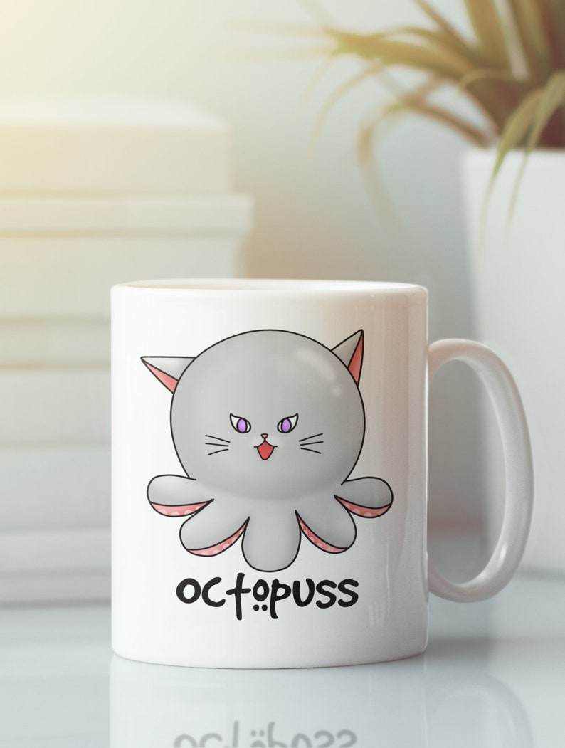 May include: White ceramic mug with a cartoon octopus with cat ears and purple eyes. The octopus is gray with pink tentacles. The text "octopus" is printed below the octopus.
