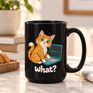 Op de afbeelding: Een zwarte keramische mok met een cartoon van een oranje cyperse kat die voor een blauwe laptop zit. Op het scherm staat de tekst $ sudo rm -rf / in het groen en het woord what? staat in het wit onder de kat. De mok heeft een gebogen oor.