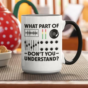Könnte beinhalten: Weiße Keramik-Kaffeetasse mit schwarzem Rand und Henkel. Die Tasse zeigt eine Grafik eines Mischpults mit dem Text "What part of -don't you- understand?"