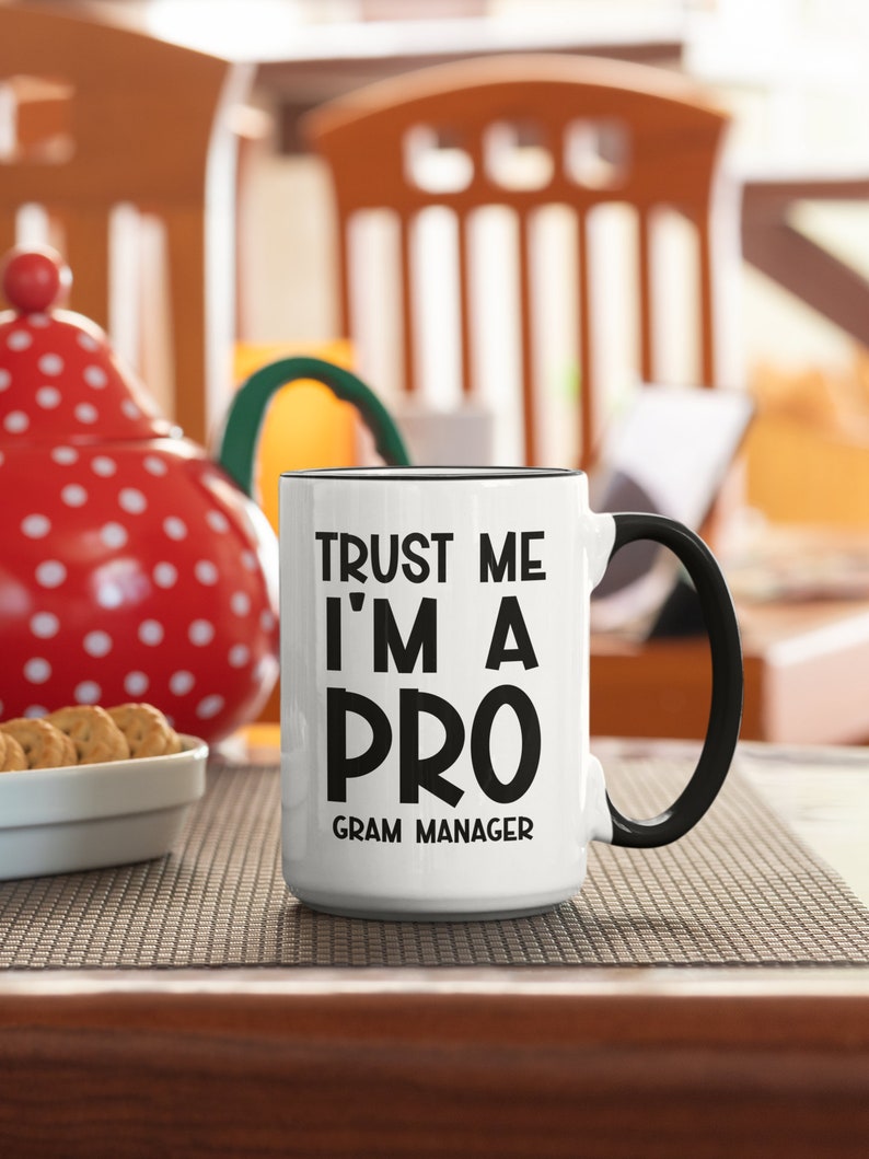May include: White ceramic mug with a black handle and black text that reads "Trust me I'm a pro Gram Manager".