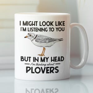 May include: White ceramic coffee mug with a black and white illustration of a bird and the text "I might look like I'm listening to you but in my head I'm thinking about plovers".