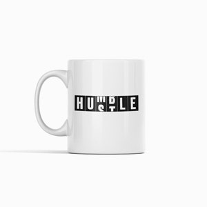 Peut inclure: Une tasse en c&eacute;ramique blanche avec un motif noir qui dit "HUSTLE" dans une police de caract&egrave;res en blocs.