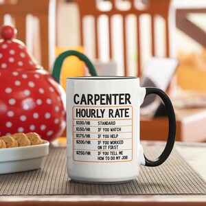 May include: White ceramic coffee mug with a black handle. The mug has a black border and the text "CARPENTER HOURLY RATE" in black. The text is followed by a list of hourly rates and descriptions, such as "$100/HR STANDARD", "$150/HR IF YOU WATCH", "$175/HR IF YOU HELP", "$200/HR IF YOU WORKED ON IT FIRST", and "$250/HR IF YOU TELL ME HOW TO DO MY JOB".