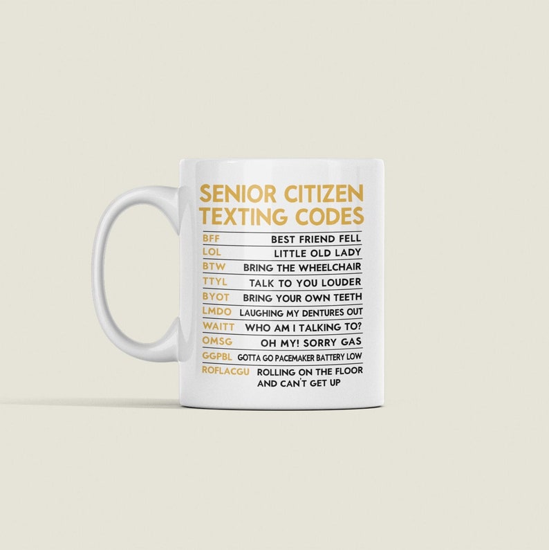 May include: White ceramic mug with a curved handle. The mug features the text "SENIOR CITIZEN TEXTING CODES" in gold lettering, along with a list of texting abbreviations and their meanings. A humorous gift idea.