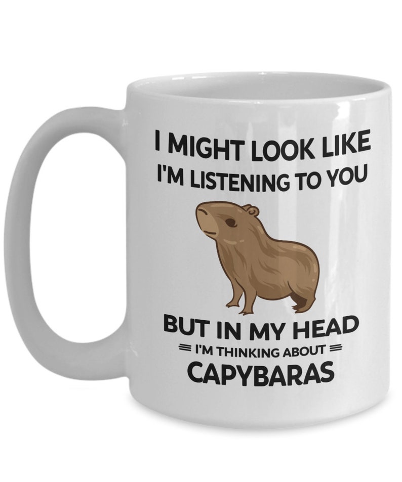 K&ouml;nnte beinhalten: Wei&szlig;e Keramik-Kaffeetasse mit einer schwarzen Grafik eines Capybaras und dem Text "Ich sehe vielleicht aus, als w&uuml;rde ich zuh&ouml;ren, aber in meinem Kopf = Denke ich an = Capybaras".