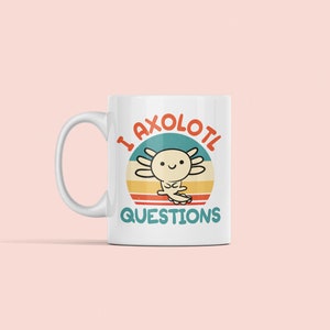 Pode incluir: Caneca de cer&acirc;mica branca com um gr&aacute;fico retro colorido de um axolote com o texto "I axolotl questions".