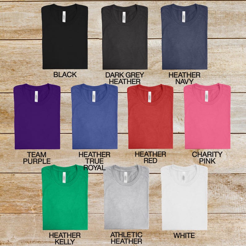 May include: A selection of t-shirts in various colors, including black, dark grey heather, heather navy, team purple, heather true royal, heather red, charity pink, heather kelly, athletic heather, and white.