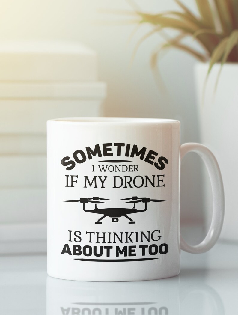 Op de afbeelding: Een witte keramische mok met een zwarte afbeelding waarop staat "Sometimes I wonder if my drone is thinking about me too". De afbeelding bevat ook een zwart silhouet van een drone.