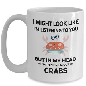Pu&ograve; includere: Tazza da caff&egrave; in ceramica bianca con una grafica in bianco e nero di un granchio e il testo "I might look like I'm listening to you but in my head = I'm thinking about = CRABS".