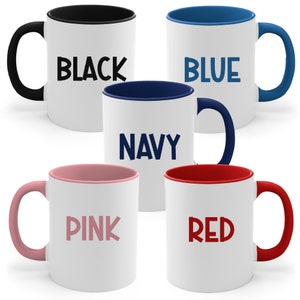 May include: Five ceramic mugs with different coloured rims and text. The mugs are black, blue, navy, pink, and red. The text on the mugs reads "BLACK", "BLUE", "NAVY", "PINK", and "RED".