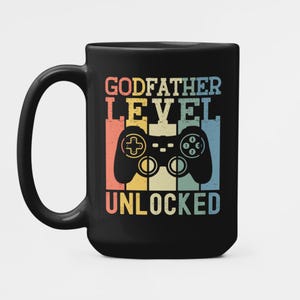 Könnte beinhalten: Schwarze Kaffeetasse mit einem Retro-Design mit einem Videospiel-Controller und dem Text "Godfather Level Unlocked".
