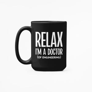 May include: Black ceramic mug with a white handle. The mug features the text "RELAX I'M A DOCTOR (OF ENGINEERING)" in a bold, white font. The mug is designed for hot beverages.