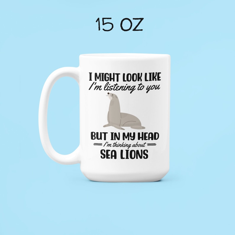 May include: White ceramic mug with a black and grey sea lion illustration. The mug reads "I might look like I'm listening to you, but in my head I'm thinking about sea lions".