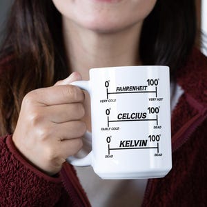 Op de afbeelding: Witte keramische mok met een zwart temperatuurschaalontwerp. De mok heeft schalen voor Fahrenheit, Celsius en Kelvin, met temperatuurbereiken van "Zeer koud" tot "Zeer heet" en "Dood".