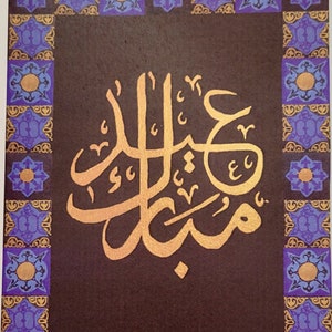 May include: A greeting card with a gold Arabic calligraphy design on a dark brown background. The calligraphy is surrounded by a purple and gold border.