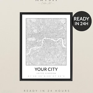 May include: A framed black and white map print featuring a detailed city map. The text "YOUR CITY" is displayed, along with the country and coordinates. The print also includes the text "READY IN 24 HOURS".