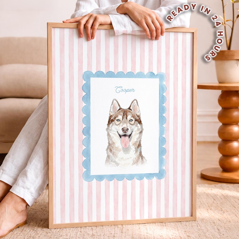 以下が含まれることがあります： 舌を出した茶色と白のハスキー犬の水彩画イラストが描かれた額入りプリント。犬は水色のスカラップ模様の枠内に配置され、背景は淡いピンクと白の縦縞模様になっている。