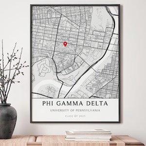 May include: Framed black and white map print with a red marker pin. The print features a detailed city map with the text "PHI GAMMA DELTA, UNIVERSITY OF PENNSYLVANIA, CLASS OF 2025" in a clean, modern font.