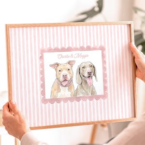 以下が含まれることがあります： ベージュのピットブルとグレーのワイマラナーの2匹の犬の水彩画イラストが描かれた額入りプリント。上部には「Charlie & Maggie」の文字があり、背景は淡いピンクと白の縦縞模様で、イラストの周りにはスカラップ状の縁取りが施されています。