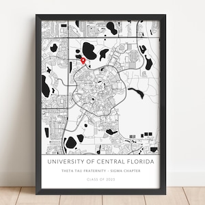 May include: Black and white framed map print of the University of Central Florida, with a red marker pinpointing a location. The print includes the text "UNIVERSITY OF CENTRAL FLORIDA", "THETA TAU FRATERNITY - SIGMA CHAPTER", and "CLASS OF 2025".