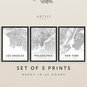 May include: Set of three framed city map prints. The maps are in black and white, featuring Los Angeles, Philadelphia, and New York. The text at the bottom reads "SET OF 3 PRINTS" and "READY IN 24 HOURS". The brand name "ARTSIF" is at the top.