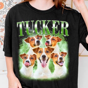 A black t-shirt with a graphic design featuring five brown and white dogs with their tongues out, surrounded by a green and white background.