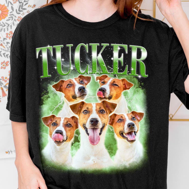 A black t-shirt with a graphic design featuring five brown and white dogs with their tongues out, surrounded by a green and white background.