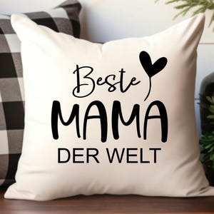 May include: White pillow with black text that reads "Beste Mama Der Welt" with a black heart above the word "Mama".
