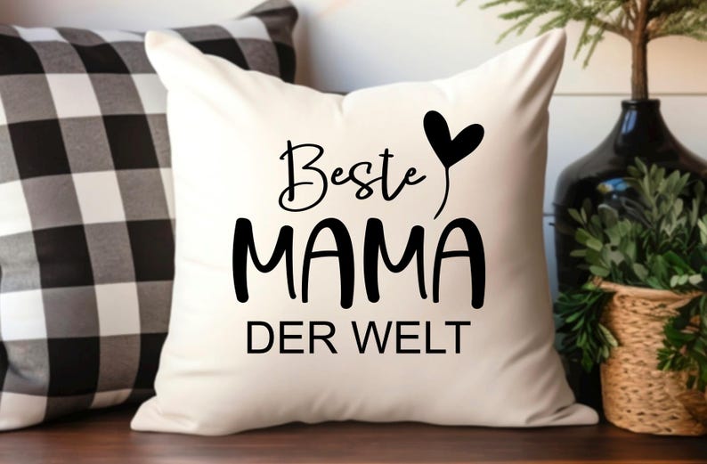 May include: White pillow with black text that reads "Beste Mama Der Welt" with a black heart above the word "Mama".